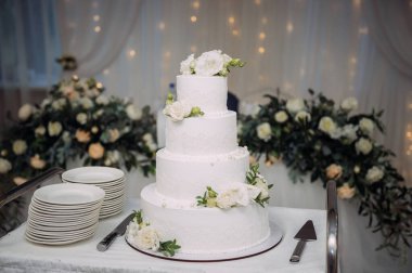 Yeşil yapraklarla süslenmiş dört katlı bir pasta..