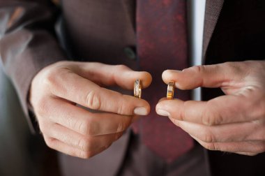 Genç bir adam elinde altın alyanslar tutuyor..