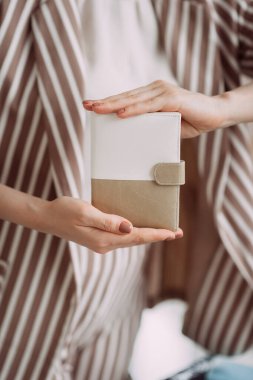 Çizgili ceketli bir kız el yapımı kapaklı bir kitap sunar..