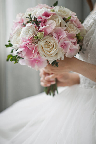 A large bouquet of white and pink roses in the hands of the bride.