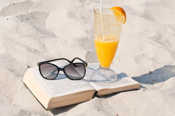 kitap ve bir kum plajı üzerinde güneş gözlüğü