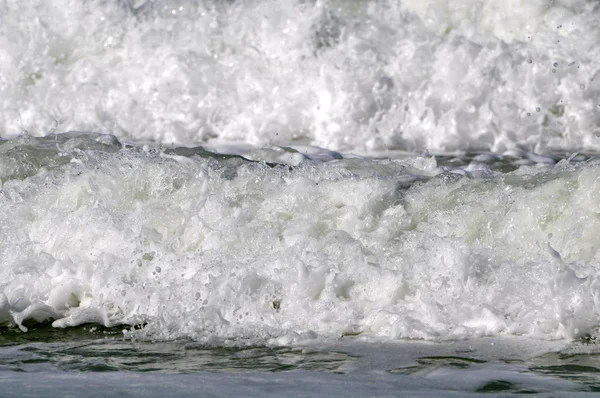 Espuma de mar branca em uma praia — Fotografia de Stock