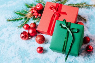Mavi arka planda, içinde Noel oyuncakları olan kutular tüylü ladin konfeti dalıyla parıldıyor. Yılbaşı konsepti. Fotokopi alanı olan düz şenlik modeli