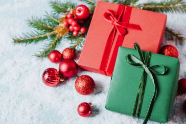 Mavi arka planda, içinde Noel oyuncakları olan kutular tüylü ladin konfeti dalıyla parıldıyor. Yılbaşı konsepti. Fotokopi alanı olan düz şenlik modeli