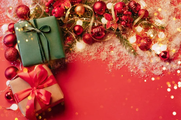 Caixas festivas em um fundo vermelho com bolas de brinquedos de Natal um ramo de abeto fofo, brilhos com luzes de confete. Conceito de Natal de Ano Novo. Mockup festivo plana com espaço de cópia — Fotografia de Stock