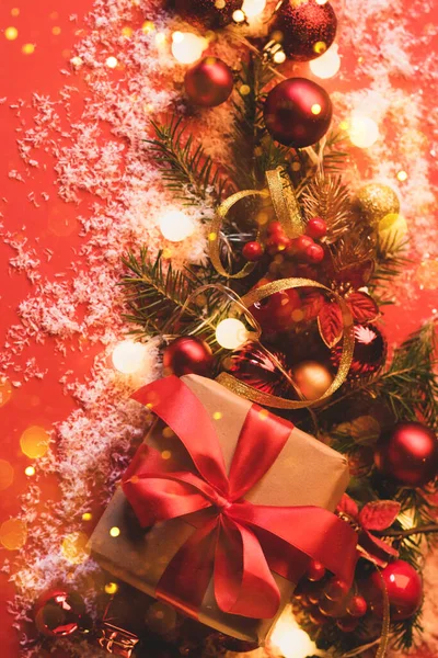 Caixas festivas com um arco vermelho de cetim em um fundo vermelho com bolas de brinquedos de Natal, um ramo de abeto fofo, brilhos com luzes de confete. Ano Novo Plano mockup festivo com espaço de cópia — Fotografia de Stock