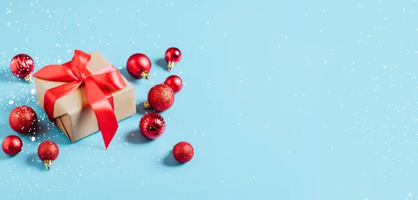 Belle palle rosse di Natale e regalo di Capodanno con un nastro rosso che decora i giocattoli su sfondo blu. Il concetto di Natale di Capodanno. Mockup festivo piatto con spazio di copia — Foto Stock