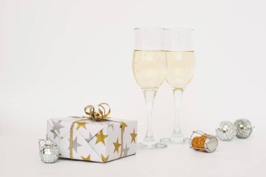 İki zarif kadehte şampanya, Noel hediyesi, oyuncaklar hafif arka plan. Noel ve yeni yıl kış tatili konsepti