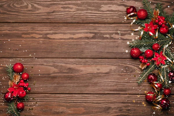 Святковий різдвяний фон червоні кульки зелені гілки ялини зміїні блискітки дерев'яний темний фон . — стокове фото