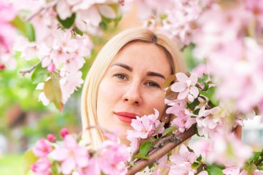 Çiçek açan ağaçların arasında genç bir kadın. Bahar parkı ya da bahçe, çiçek açan ağaçlar. Bahar kadın sağlığı kavramı