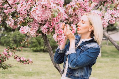 Çiçek açan ağaçların arasında genç bir kadın. Bahar parkı ya da bahçe, çiçek açan ağaçlar. Bahar kadın sağlığı kavramı
