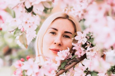 Çiçek açan ağaçların arasında genç bir kadın. Bahar parkı ya da bahçe, çiçek açan ağaçlar. Bahar kadın sağlığı kavramı