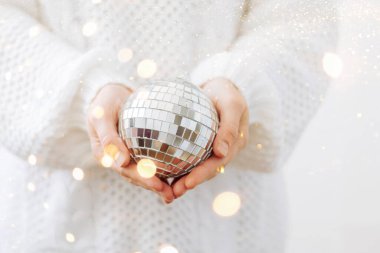 Beyaz kazaklı bir kız elinde parlak bir disko topu Noel oyuncağı tutuyor. Yılbaşı partisi konsepti.