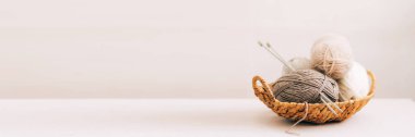Hasır sepetin içinde çeşitli pastel renklerde doğal yün. Hafif arkaplanda örgü iplikleri yakın plan.