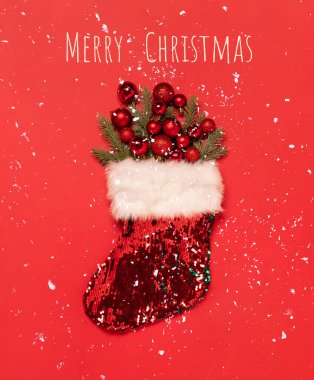 Kırmızı arka planda kırmızı oyuncak topları olan Noel çorabı. Kış gelenekleri, tatil hazırlıkları. Kutlama düzlemi 