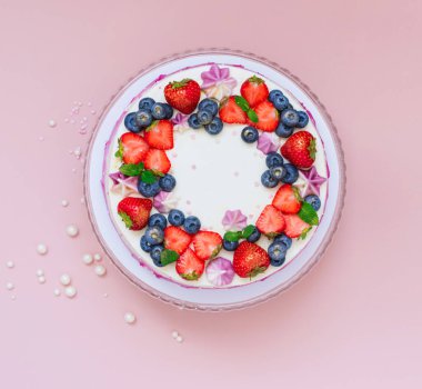 Pembe arka planda taze çileklerle süslenmiş narin bir pasta. Böğürtlenli tatlı