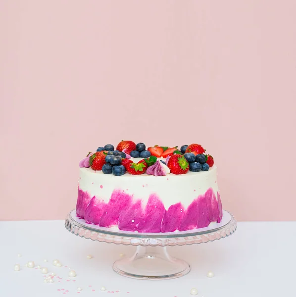Ніжний торт, прикрашений свіжими ягодами, полуницею та чорницею на світлому звичайному тлі — стокове фото