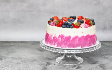 Gri arka planda taze çileklerle süslenmiş lezzetli bir pasta. Şenlikli tatlı.