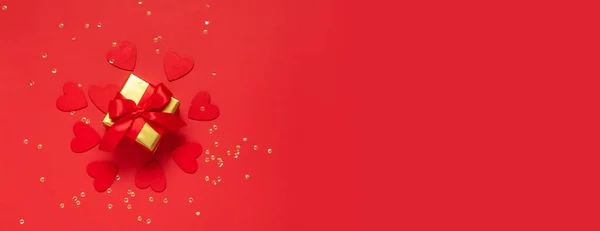 Regalo con lazo rojo sobre fondo rojo con corazones brillantes y confeti. Composición plana festiva para San Valentín, Año Nuevo, Día de las Madres, Boda. Burla con espacio de copia —  Fotos de Stock