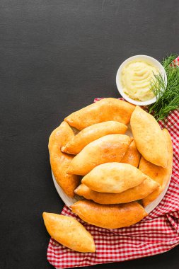 Kıtır kıtır patatesli küçük turtalar siyah arka planda bir tabakta duruyor. Ev yapımı ülke yemekleri.