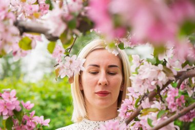 Çiçek açan ağaçların arasında genç bir kadın. Bahar parkı ya da bahçe, çiçek açan ağaçlar. Bahar kadın sağlığı kavramı