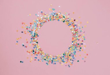 Renkli konfeti dizileri yuvarlak çerçeveli pembe arka planda. Metin için soyut şenlik kompozisyonu