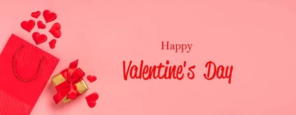 Bolso de papel rojo, corazones rojos y lazo de raso regalo con lazo de fondo rosa. Fondo festivo día de San Valentín — Foto de Stock