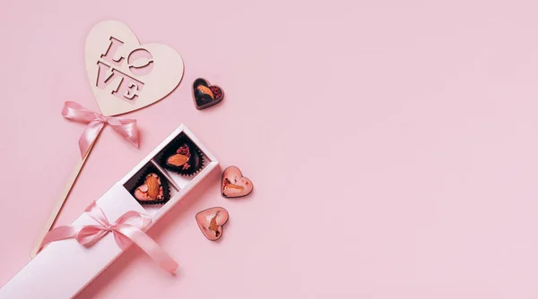 Праздничная композиция ко Дню Святого Валентина. Шоколадные конфеты сердца атлас летом на розовом фоне. Плоская квартира — стоковое фото