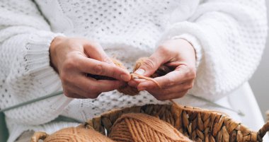 Kadın elleri örgü örmekle meşguldürler. Örgü örmek için iplikler, örgü şişleri yakın çekim, seçici yumuşak odak. Hobi olarak ev örgü örüyorum.