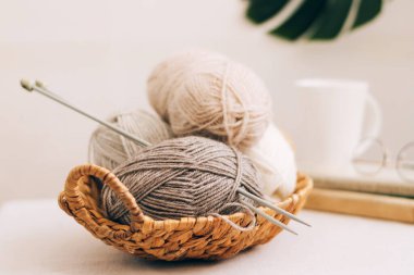 Hasır sepetin içinde çeşitli pastel renklerde doğal yün. Hafif arkaplanda örgü iplikleri yakın plan.