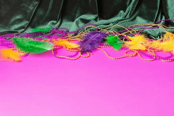 Festive carnival background, green velvet curtain colorful feather beads necklace for Mardi Gras — Stock Photo, Image