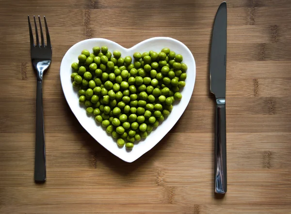 Guisantes verdes en un plato en forma de corazón —  Fotos de Stock