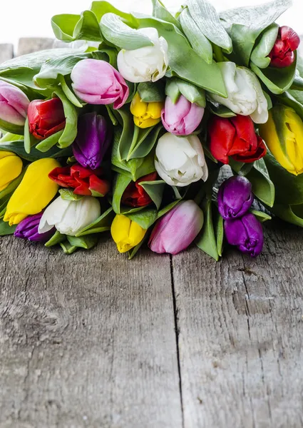 Цветные тюльпаны на старом деревянном столе — стоковое фото