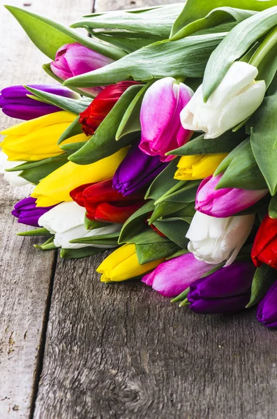 Цветные тюльпаны на старом деревянном столе — стоковое фото