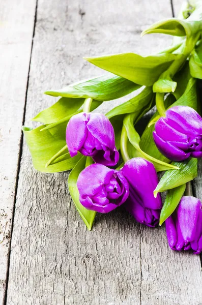 Фиолетовые тюльпаны на старом деревянном столе — стоковое фото