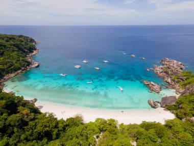 Tayland 'ın Similan Adaları' ndaki bir adanın güneşli gökyüzü ve biraz bulut mavisi gökyüzü ve zümrüt suyu ile güneşli gün ışığında üst ve hava manzarası..