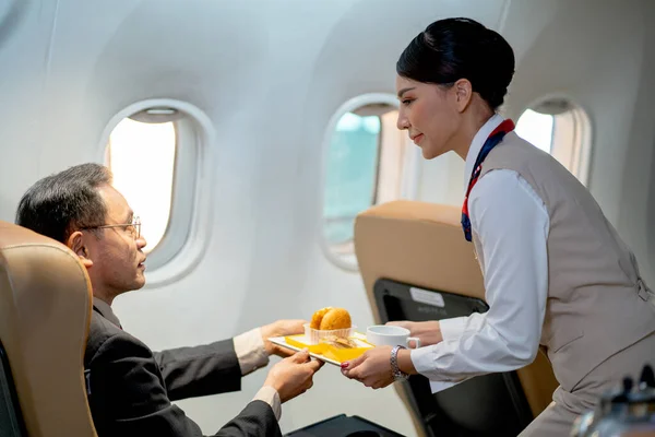 Air hostess or cabin crew serve dessert and cake to the passenger or business man during the flight for working in other country.