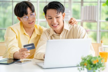 Gay ya da Igbt erkekleri dizüstü bilgisayarlarını kullanarak online alışverişe çıkarlar ve gün ışığıyla oturma odasında kalırlar..