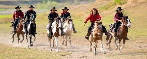 一群牛仔和牛仔女骑着马走在水塘附近的高速公路上 白日光彩夺目 — 图库照片