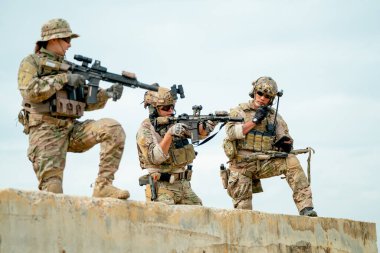 Military or soldier team with gun stay on concrete wall and prepare for battle with enemy in field with day light.