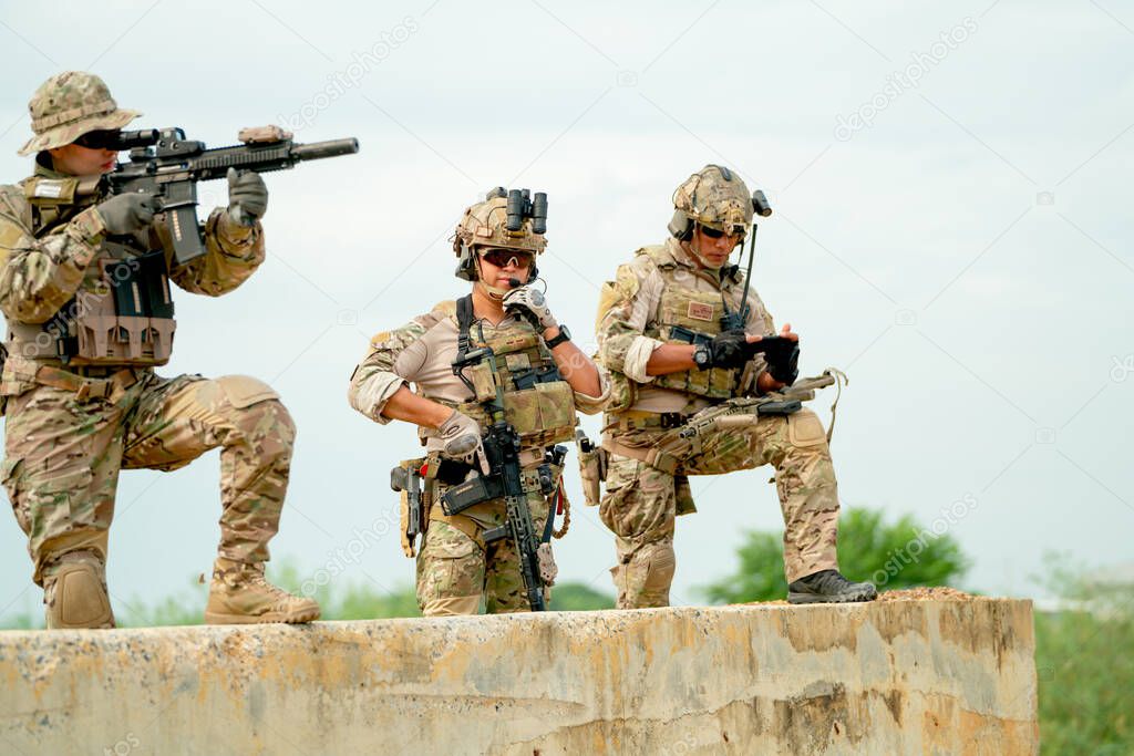 Military or soldier team with gun stay on concrete wall and prepare for battle with enemy in field with day light.