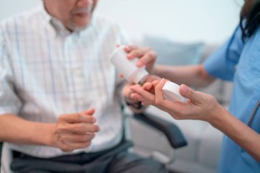 Hemşirelerin ya da doktorların ellerini kapatın ve evde bakım için sağlık desteği sürecinde yaşlı adama ilaç vermeye ve açıklama yapmaya yardım edin..