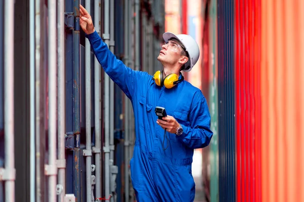 Cargo container worker or technician with safety protection and blue uniform walk to check the product in workplace and stay in channel between container tank.