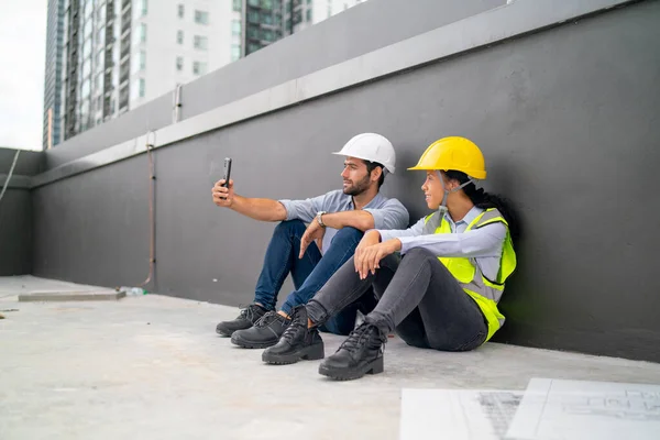 Two engineer or technician workers use mobile phone to selfie after finish work in construction site.