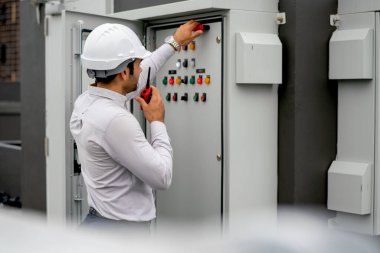 Caucasian engineer man or technician using walkie talkie to contact his coworker and ask for support about electrical control panel in construction site.