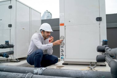 Engineer man or technician sit and  use walkie talkie to contact his team for maintenance of tank system in construction site.