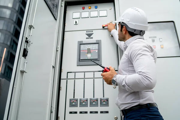 Different actions and working of engineer man hold walkie talkie and sometime use to contact his coworker and stay in front of electrical control panel.