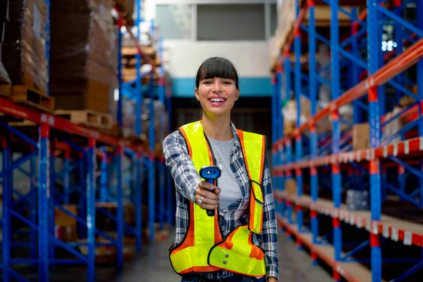 Portrait of Cacuasian warehouse worker hold barcode scaner and point at camera stay on way between shelves in workplace. Concept of professional factory worker support for delivery system.