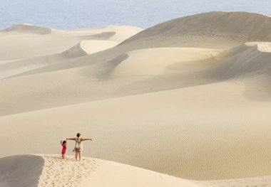 Woman and daughter walking in the dunes of Maspalomas