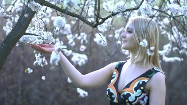 Mujeres jóvenes oliendo a flores en el jardín — Vídeo de stock